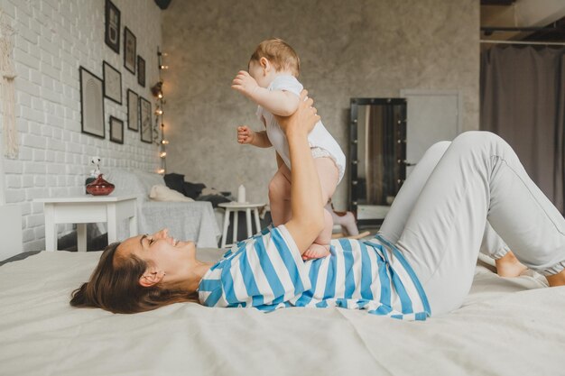 Retrato de madre e hijo riendo y jugando en la cama en casa