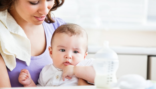 Retrato de una madre encantadora que cuida a su bebé adorable en la cocina