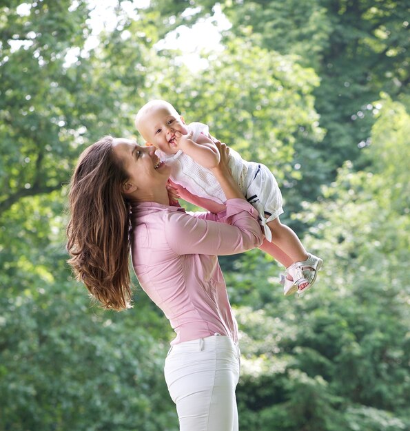 Retrato de una madre feliz jugando con bebé en el parque