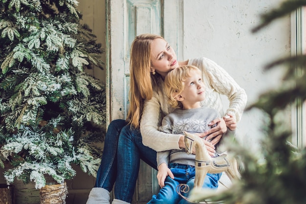Retrato de madre feliz y niño adorable celebran la Navidad. Vacaciones de año nuevo