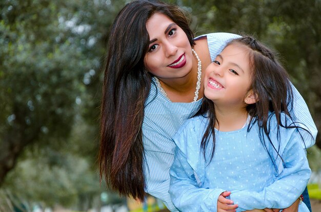 Foto retrato de una madre y una hija felices abrazándose en el parque