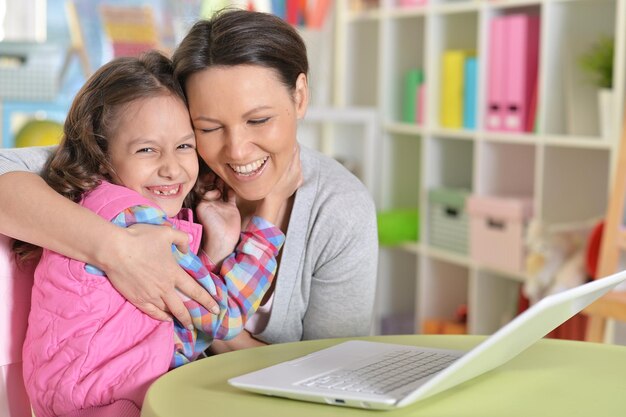 Retrato de una madre y una hija felices usando una computadora portátil
