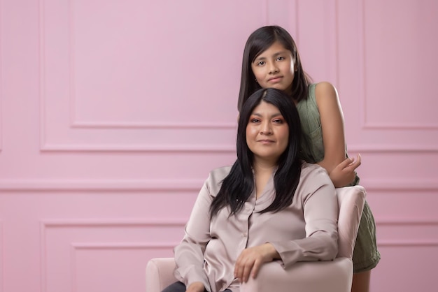 Retrato de una madre mexicana y su hija aislado sobre fondo de color rosa