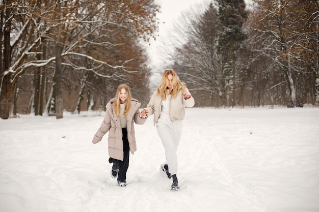 Retrato de madre rubia e hija adolescente corriendo en el bosque de invierno