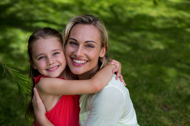 Retrato de la madre sonriente con su hija en el patio