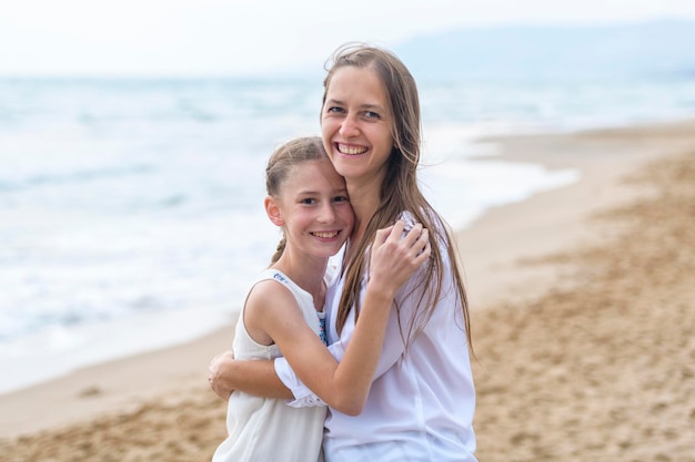 Retrato de una madre con su hija de pie en la playa