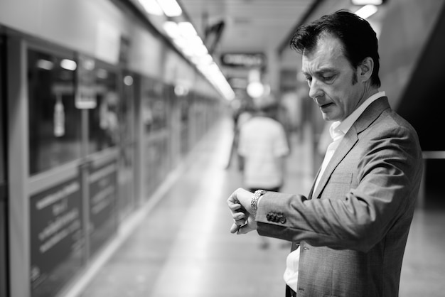 Retrato de maduro empresario guapo explorando la ciudad en blanco y negro