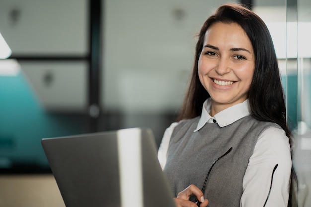 Retrato de una maestra segura de sí misma que trabaja en una computadora portátil escribiendo nuevas publicaciones para las redes sociales