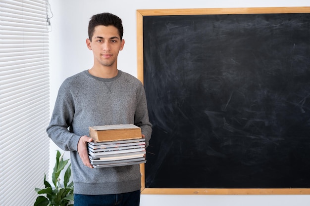 Retrato de un maestro árabe con libros en el fondo de la pizarra de regreso a la escuela concepto educación y conocimiento