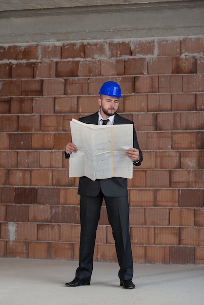 Retrato de maestro de la construcción con casco azul y Blueprint en manos