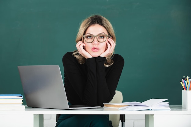 Retrato de maestro en la escuela con computadora portátil en el aula en la pizarra