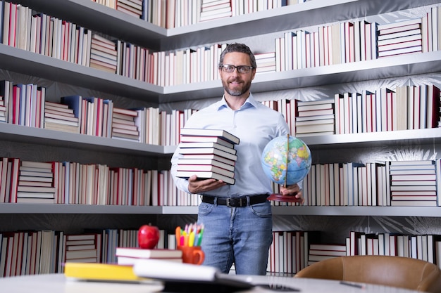 Retrato de un maestro de escuela con un libro en el aula un maestro guapo en el aula los maestros tienen un buen día