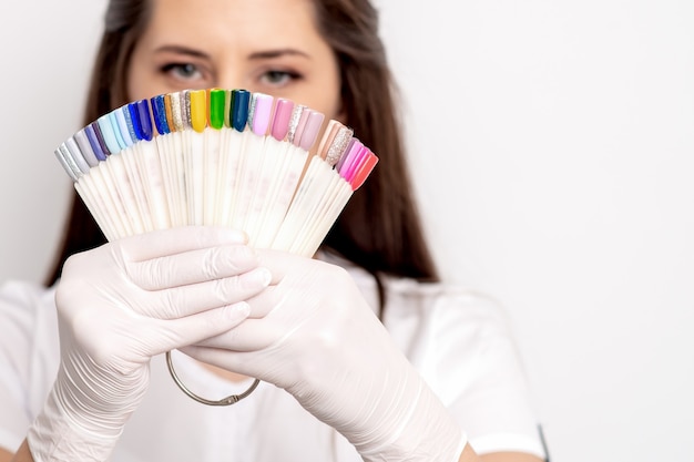 Retrato de maestro de manicura con paleta de muestra de uñas en blanco