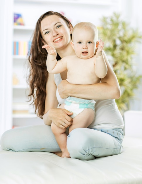 Retrato de mamá feliz con un niño de un año en el fondo de la habitación de un niño