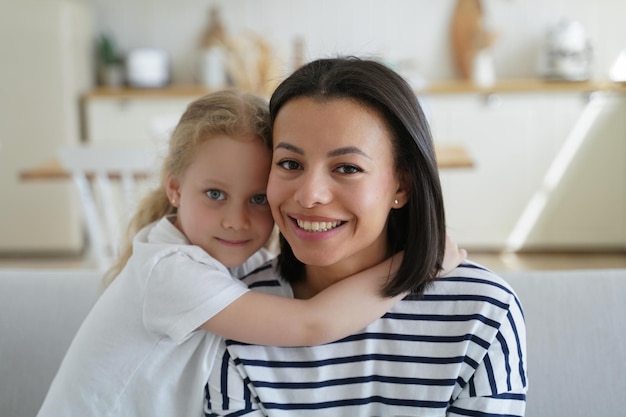 Retrato de mamá y niña linda Niño rubio abraza a mamá Mujer guapa y niña juntas en casa