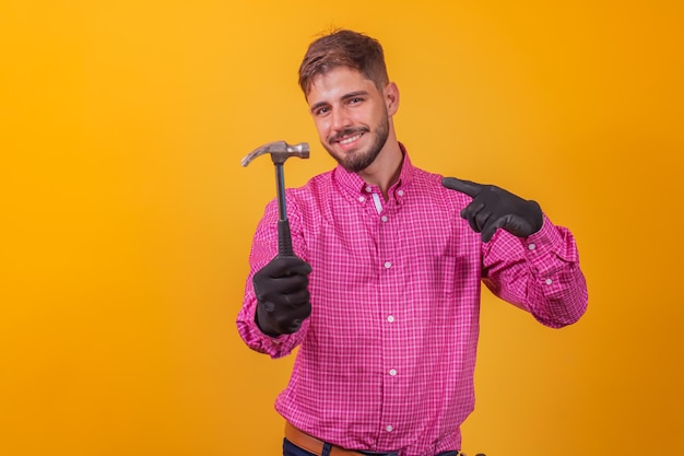 Retrato de un manitas feliz sosteniendo un martillo sobre fondo amarillo.