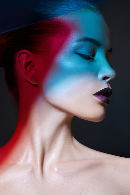 Retrato de maquillaje de belleza contrastante brillante de una mujer en tonos de sombra azul y rojo