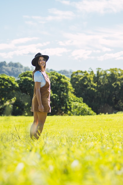 Retrato de maravillosa modelo mujer blanca con sombrero mientras camina por el campo