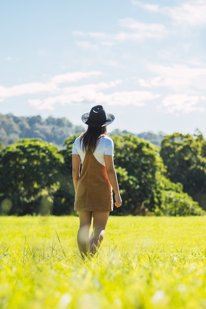 Retrato de maravillosa modelo mujer blanca con sombrero mientras camina por el campo