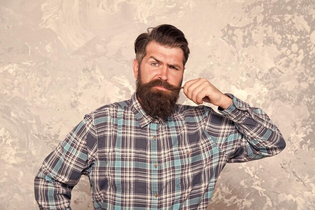 retrato de la masculinidad hombre elegante de moda fondo grunge hombre guapo con camisa a cuadros hipster maduro toca su bigote peluquero y barbería cuidado del cabello y la barba