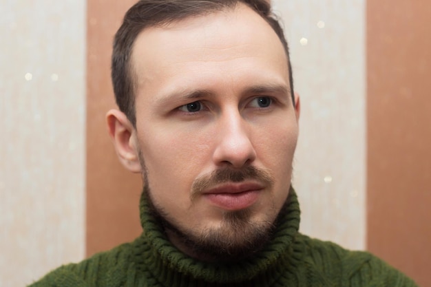 Retrato masculino de un hombre en un suéter verde sentado en un sofá