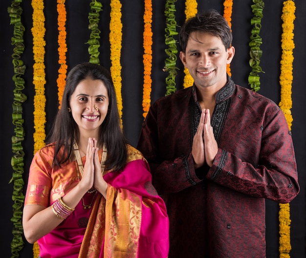 Retrato de matrimonio indio en ropa tradicional en Namaskara o oración o pose de bienvenida o sosteniendo puja thali