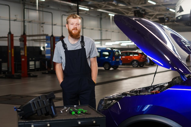 Retrato de un mecánico de automóviles profesional con un uniforme limpio en el contexto de un moderno centro de reparación de automóviles