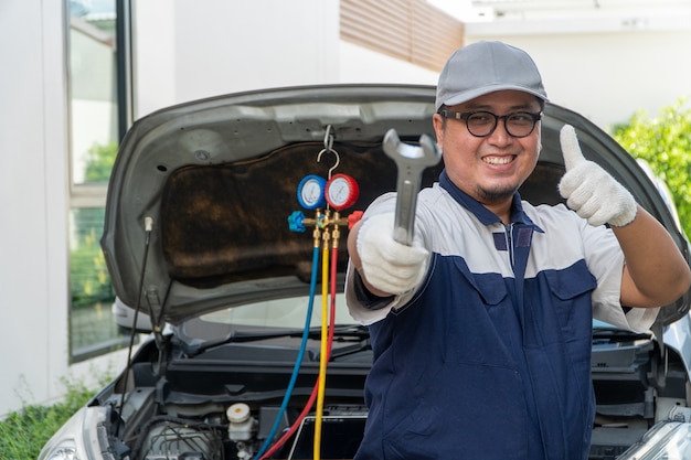 Retrato de un mecánico de automóviles sosteniendo una llave en un taller de reparación de automóviles. Concepto de reparación de máquinas