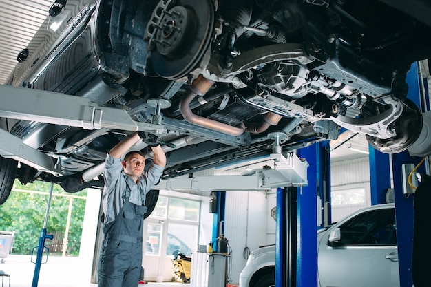 Retrato de un mecánico reparando un coche levantado.