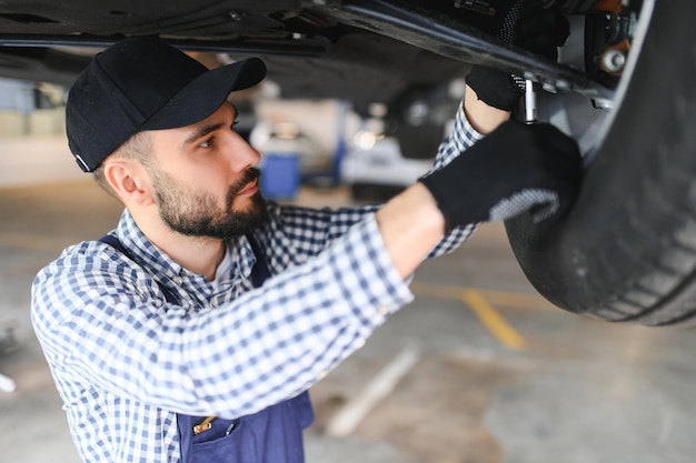 Retrato de un mecánico reparando un coche levantado