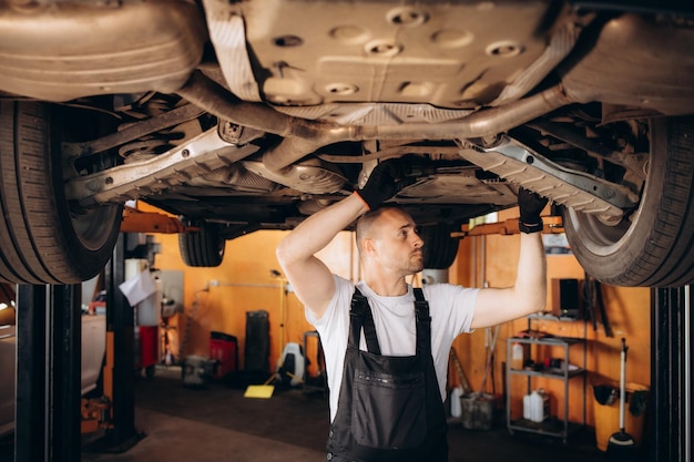 Retrato de un mecánico reparando un coche levantado