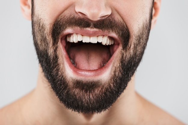 Retrato de media cara de un hombre barbudo sonriente aislado sobre blanco de cerca