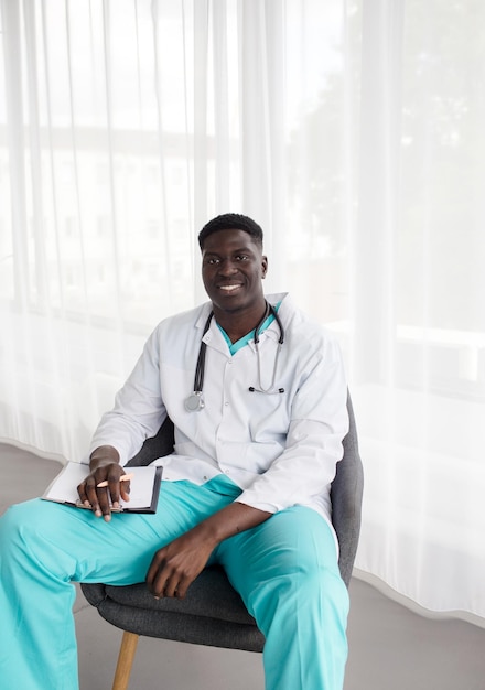 Retrato de un médico africano sentado en una silla sonriendo