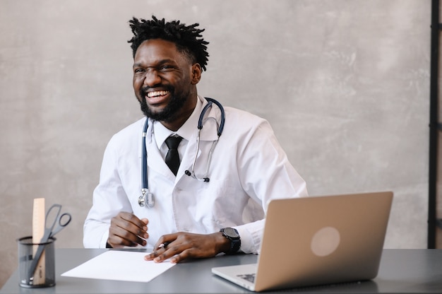 Retrato de médico afroamericano con ordenador portátil. consulta online.