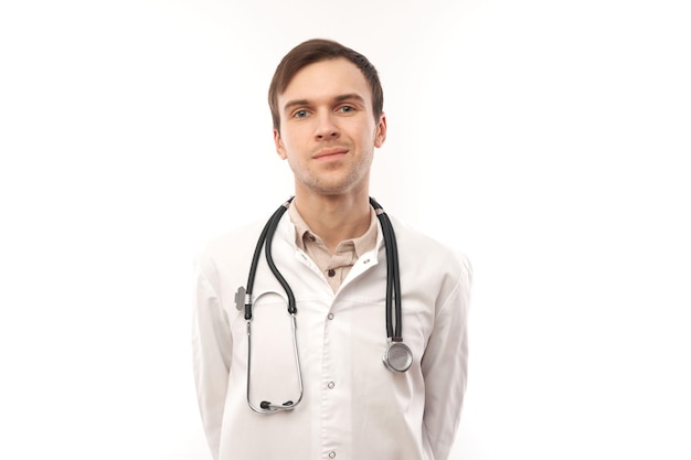 Retrato de un médico apuesto con bata médica blanca con estetoscopio sobre fondo blanco con espacio para copiar