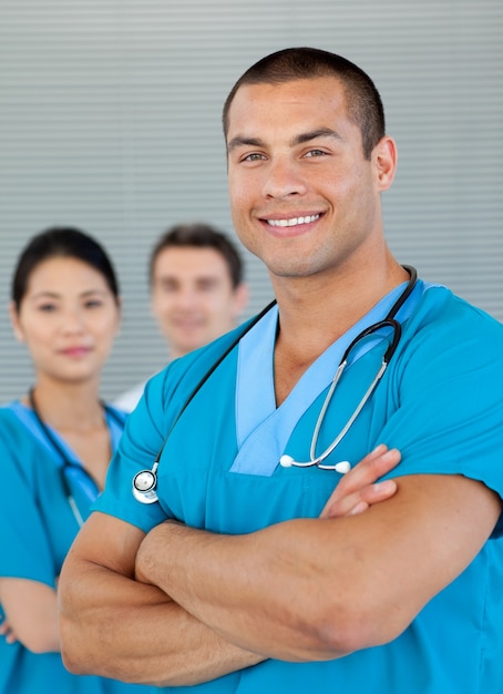 Retrato de un médico atractivo con sus colegas en el fondo