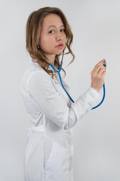 Retrato de un médico en bata con un estetoscopio en la mano aislado sobre fondo blanco.