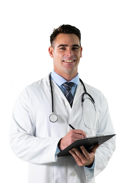 Retrato de un médico caucásico con una bata de laboratorio y un estetoscopio, de pie sosteniendo un portapapeles tomando notas mirando a la cámara sonriendo sobre un fondo blanco.