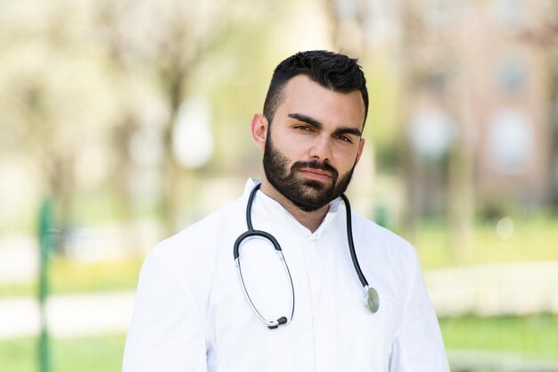 Retrato de un médico caucásico cansado y exhausto sin máscara frente a un parque - Enfermedad del virus Coronavirus Covid-19 - Brote pandémico global