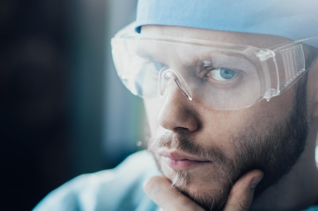 retrato de médico cirujano con gafas y uniforme médico masculino joven