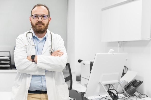 Retrato de un médico confiado cruzando las manos y sonriendo a la cámara