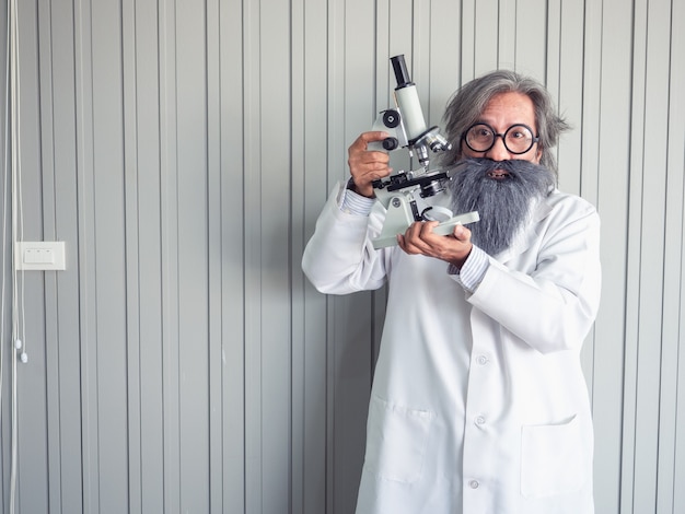 Retrato de un médico delante de un fondo gris grunge con microscopio