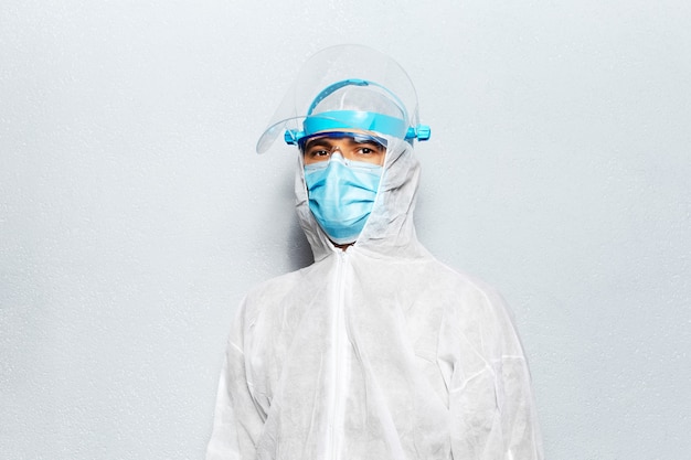 Retrato de un médico con una demanda PPE contra el coronavirus y el covid-19, en el fondo de una pared blanca. Concepto de pandemia.