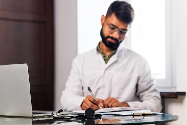 Retrato de un médico indio masculino con bata blanca en el consultorio de la clínica