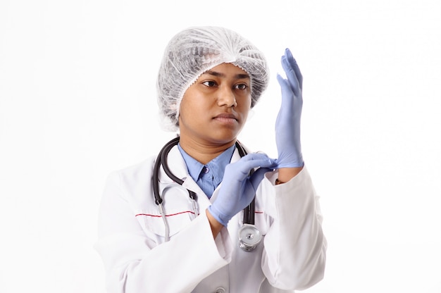 Retrato de un médico indio. Mujer con un estetoscopio se pone guantes médicos