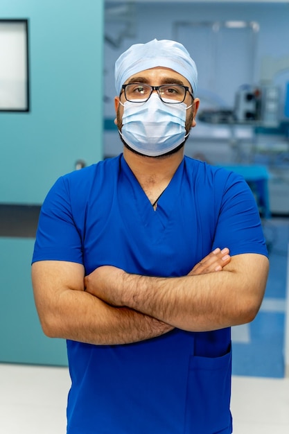 Retrato de un médico masculino en el hospital Hombre mirando a la cámara con máscara Fondo de equipo moderno
