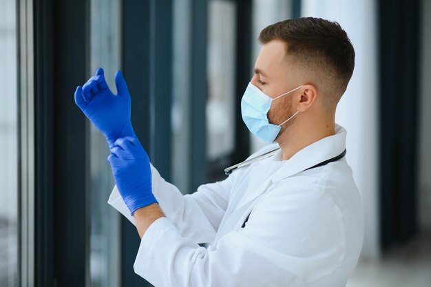 El retrato de un médico masculino que usa una máscara quirúrgica está listo para ayudar a los pacientes con coronavirus o virus covid