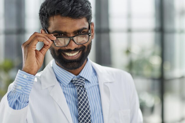 Retrato de un médico masculino sonriente oriental de pie en un pasillo del hospital