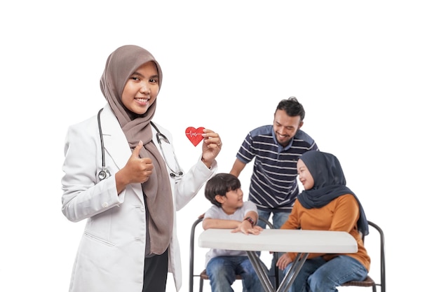 Retrato de un médico musulmán sonriendo con su familia en la visita de fondo para un chequeo médico