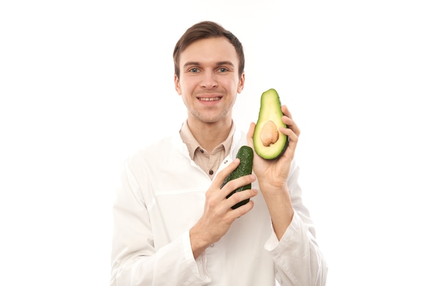 Retrato de médico nutricionista masculino sonriente positivo con aguacate.